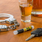 Schnapsglas mit Autoschlüssel, Alkoholtester und Handschellen Schnapsglas mit Autoschlüssel, Alkoholtester und Handschellen