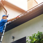 man on ladder cleaning house gutter from leaves and dirt man on ladder cleaning house gutter from leaves and dirt