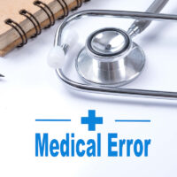 Stethoscope on notebook and pencil with Medical Error words as medical concept.
