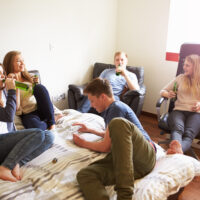 Group Of Teenagers Drinking Alcohol In Bedroom