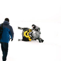 man falls off snowmobile