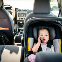 Mother and child strapped in rear-facing car seat in car