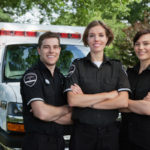Group of three paramedics standing in front of ambulance Group of three paramedics standing in front of ambulance