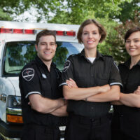 Group of three paramedics standing in front of ambulance