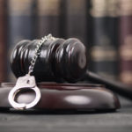 Judge Gavel and Handcuffs on a black wooden background. Judge Gavel and Handcuffs on a black wooden background.
