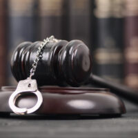 Judge Gavel and Handcuffs on a black wooden background.