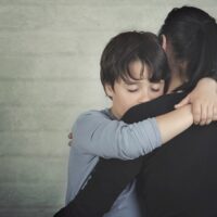 Sad child hugging his mother