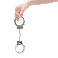 Female’s hand holding handcuffs. Isolated on white.