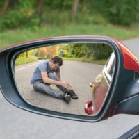 Hit and run concept. View on injured man on road in rear mirror of a car.