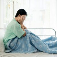Asian young woman patient lying at hospital bed feeling sad and depressed worry. Disease feeling sick in health care and clinical attention concept. Asian young woman patient lying at hospital bed feeling sad and depressed worry. Disease feeling sick in health care and clinical attention concept.