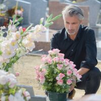 Man in black knelt at grave