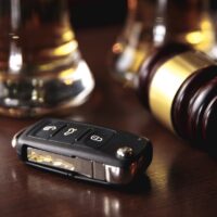 Drinking and driving concept. Car key on a wooden table, pub