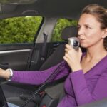 Woman blowing into breathalyzer Woman blowing into breathalyzer