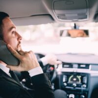 Business Man using his phone while driving the car