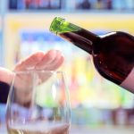 Womans hand rejecting more alcohol from wine bottle in bar Womans hand rejecting more alcohol from wine bottle in bar
