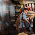 Hiding clothes. Quick professional thief hiding new clothes into his big backpack while stealing in a fashionable shop Hiding clothes. Quick professional thief hiding new clothes into his big backpack while stealing in a fashionable shop