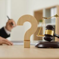Close up of a question mark and gavel on the table in the courtroom or lawyer’s office Close up of a wooden question mark and gavel on the judge