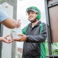 man ordering food online and receive the order at home delivered by courier