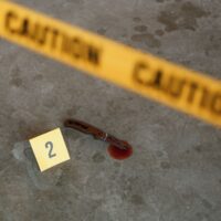 Crime scene. Top view of knife clue with blood. Police caution tape.