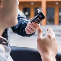 cropped view of policeman giving breathalyzer to driver in car