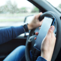 Male hands with phone. Man in car is using smartphone. Man in car is using smartphone. Concepts of ridesharing, driving safety or GPS navigation.