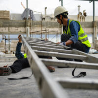 Accidents of builder in the workplace at construction site area, Builder accident falls ladder and lying on floor while foreman is helping. Working unsafe concept.