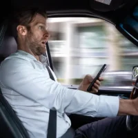 a middle aged caucasian man distracted driving while using mobile device stops suddenly to avoid accident